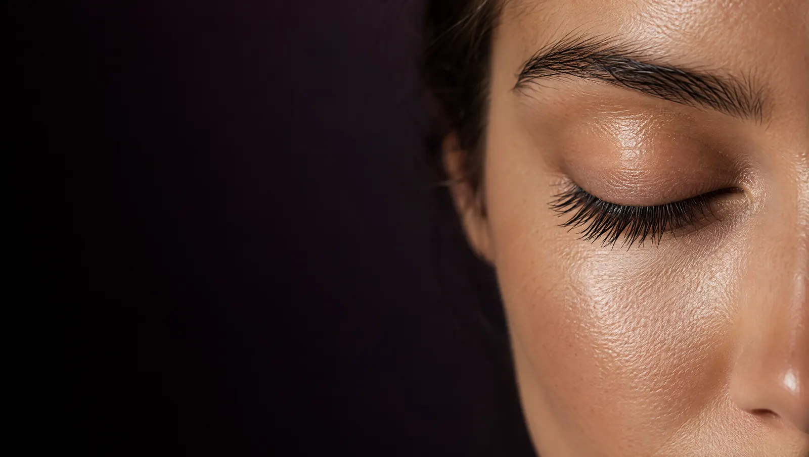 Close-up of a closed eye with long, natural eyelashes on a dark background